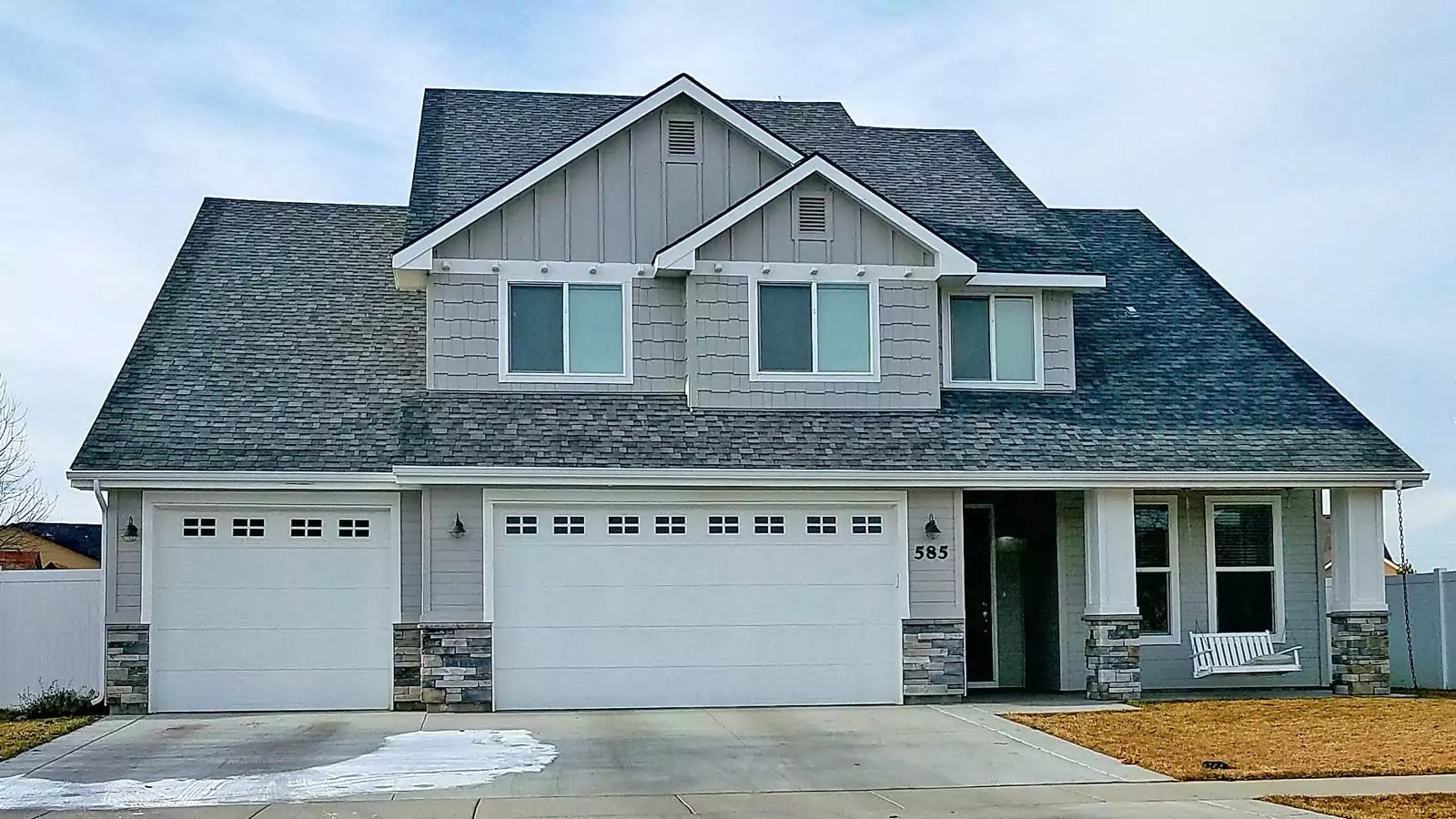 New garage doors with window rows installed on a two-story home by Overhead Door Company of Southwestern Idaho