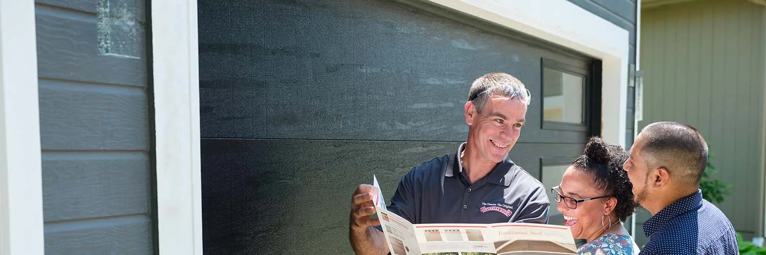 Overhead Door™ technician reviewing a brochure with homeowners